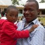 John with a child in front of the school-building.